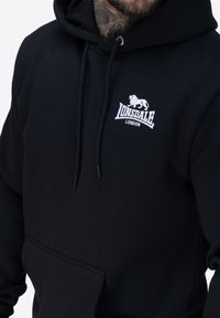 Czarna sweatshirt Lonsdale London z sznurkami, kieszenią z przodu i haftowanym logo lwa. Miękka faktura, casualowy design z kapturem.