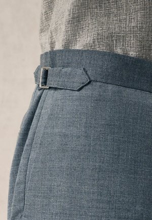 Pantaloni in tessuto blu chiaro con una finitura testurizzata, presentano una vestibilità dritta, una cintura abbinata con una fibbia rettangolare in argento e tasche laterali.