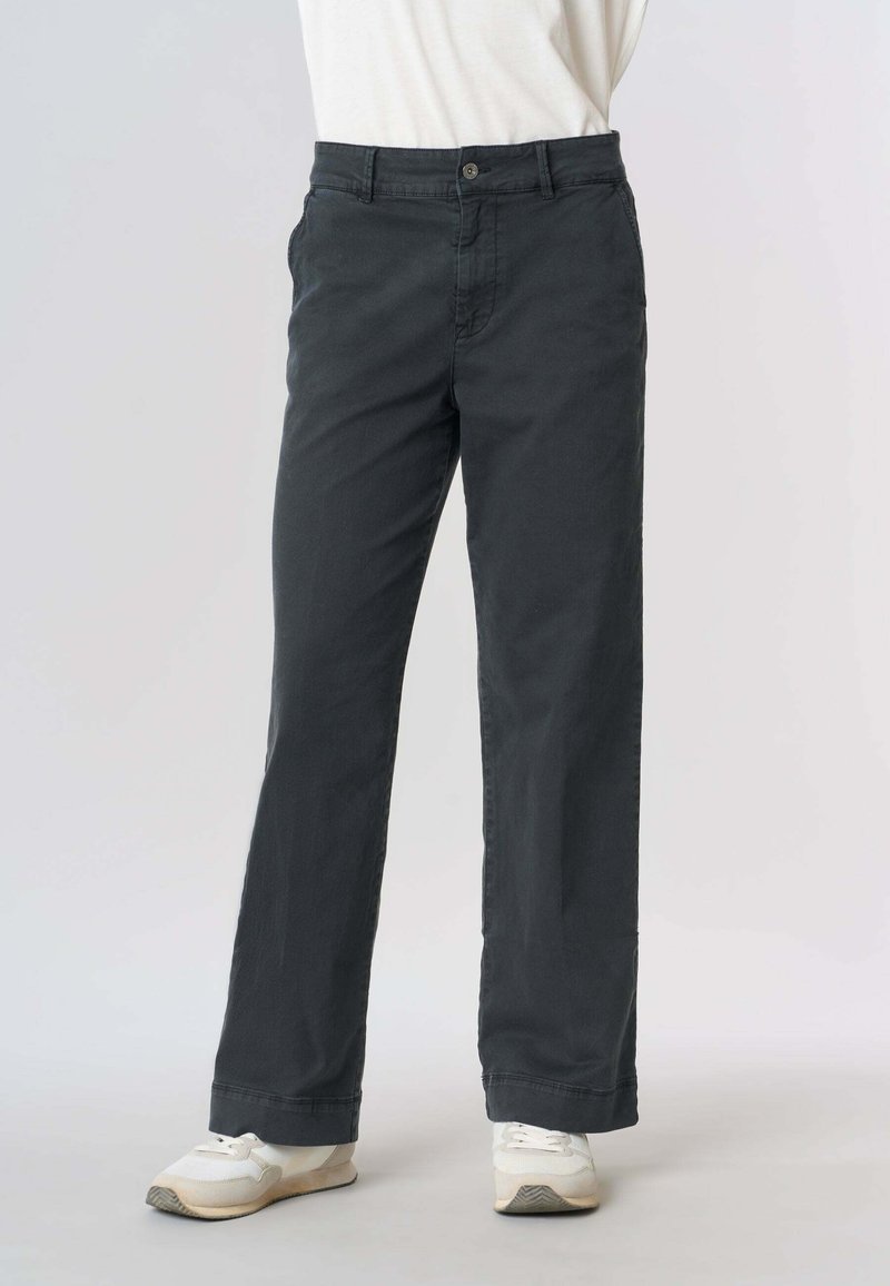Pantaloni in cotone grigio scuro con design a gamba dritta, dotati di chiusura con bottone, due tasche laterali e una texture sottile. Abbinati a scarpe sportive bianche.