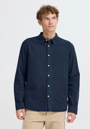 Navy blue button-up shirt made of cotton. Features a standard collar, long sleeves, and a subtle logo on the chest. Classic fit.