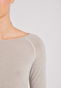 Hellgraues, langärmeliges Strickoberteil mit weitem Ausschnitt und weicher Textur. Verfügt über sichtbare Nahtdetails entlang der Schultern und des Ausschnitts.