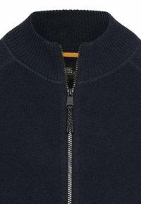Dark navy knitted sweater with a high collar and full zipper, featuring a textured fabric and contrasting zipper detail.