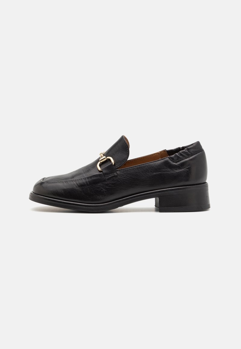Mocassin en cuir noir avec un petit talon bloc et un détail en métal doré sur le dessus, dos élastique pour un ajustement parfait.