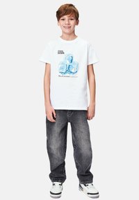 Vit t-shirt med en isbitgrafik och texten "COOL DOWN." Kombineras med grå baggy jeans och vita sneakers.