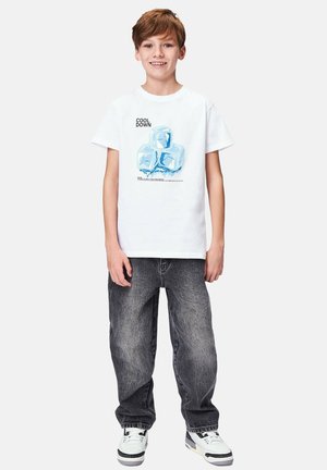 Hvid T-shirt med et isterning grafisk motiv og teksten "KØL NED." Kombineret med grå baggy jeans og hvide sneakers.