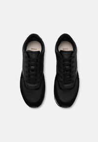 Svarte sneakers med overdel av mesh og semsket skinn, med tonale snøringer og en merket innersåle. Designet er slankt med en rund tåform.