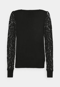 Melnas garas piedurknes krekls ar vienkrāsainu korpusu un caurspīdīgām mežģīņu piedurknēm, kurām ir ziedu raksts un pieguļoši aproces.