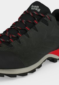 Μαύρο και κόκκινο παπούτσι πεζοπορίας με ανθεκτική σόλα, κόκκινα κορδόνια και λογότυπο "han wag" στη μαξιλαρωμένη γλώσσα.