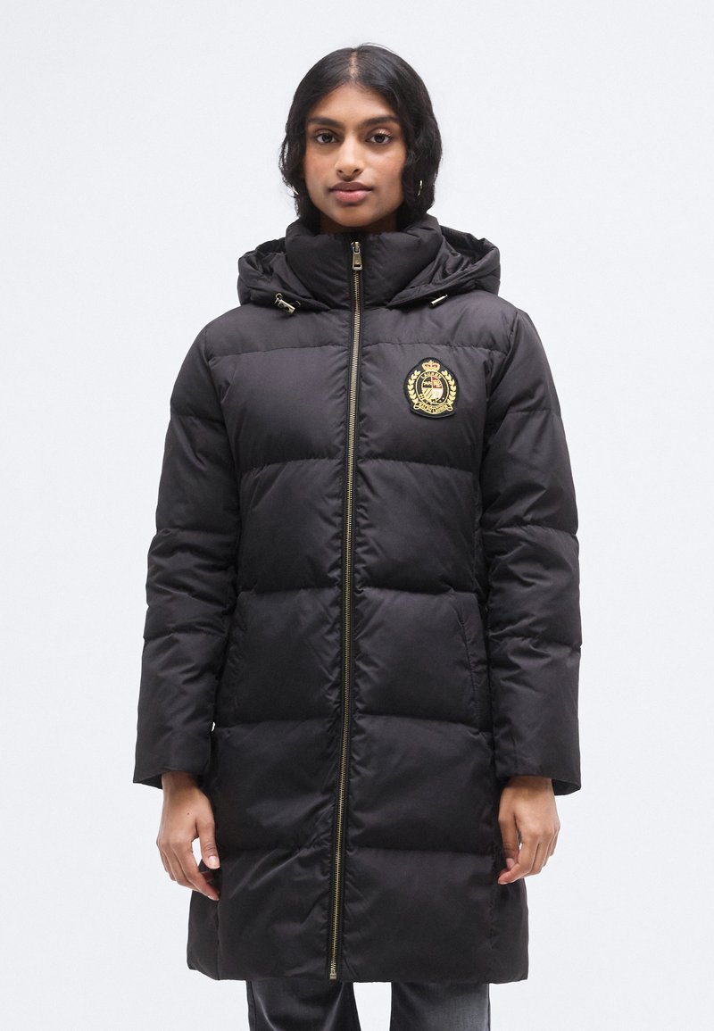 Μαύρο μπουφάν puffer με κουκούλα, που κλείνει με φερμουάρ, με λεπτομέρεια χρυσού εμβλήματος και καπιτονέ υφή. Μακριά μανίκια και μήκος έως τη μέση.