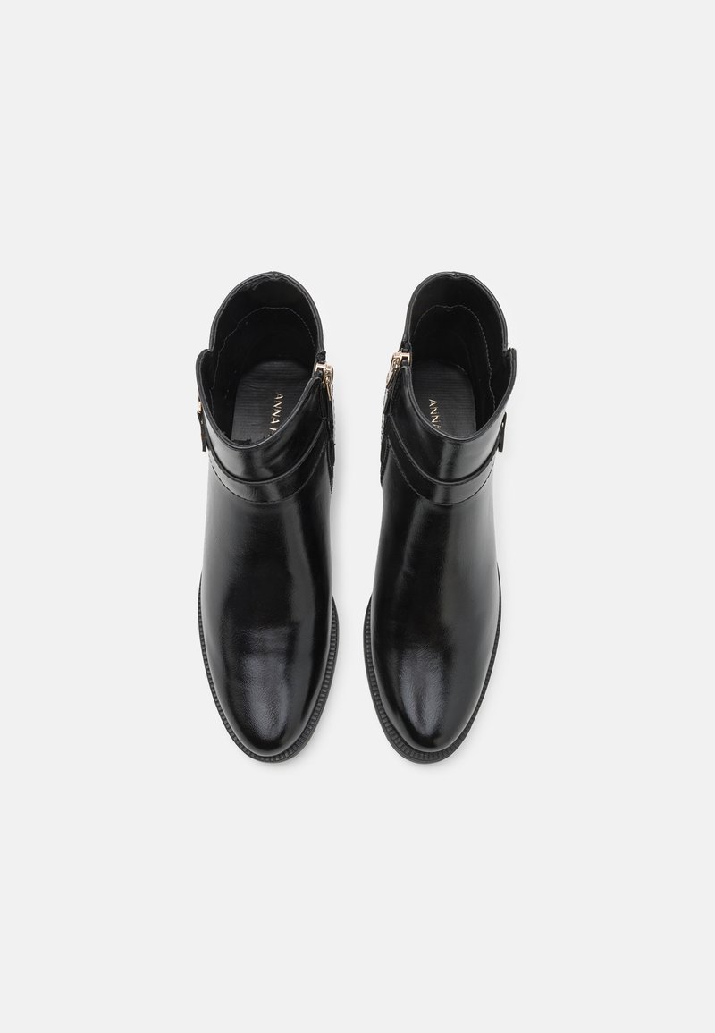 Botas de cuero negras hasta el tobillo con una textura suave, cierre de cremallera lateral, punta afilada y suela de goma de perfil bajo.