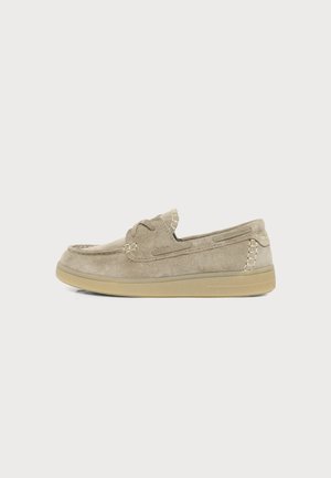 Mocassin en daim marron clair à enfiler avec couture mocassin et semelle en caoutchouc, vu de côté sur un fond uni.