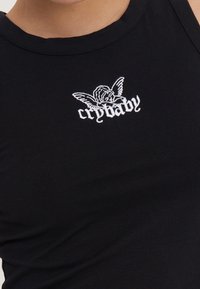 Crna pamučna majica bez rukava s bijelim izvezenim tekstom "crybaby" i grafikom anđela na prsima, s okruglim izrezom i prilagođenim dizajnom.