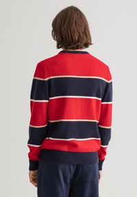 Rot gestreifter Pullover in Marineblau mit Rundhalsausschnitt, gerippten Bündchen und Saum, der horizontale Streifen in Creme und Marine zeigt. Weiche Textur.