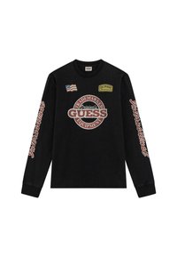 Zwarte longsleeve shirt met 'GUESS' logo en patches, met een getextureerde print en het woord 'International' in het rood langs de mouw.