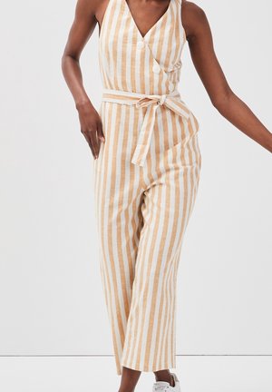 Combinaison rayée beige et blanche, avec un col en V, des boutons, une ceinture nouée à la taille et un pantalon à jambes larges pour une coupe décontractée.