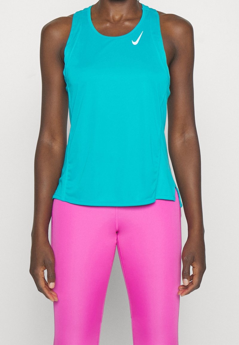 Haut de sport turquoise sans manches avec un col rond, arborant un logo blanc. Associé à des leggings moulants rose vif. Texture lisse.