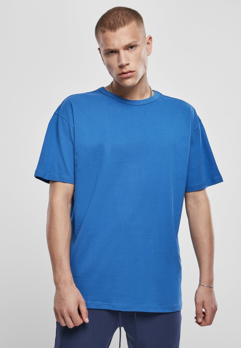 Tricou din bumbac albastru, cu guler rotund, mâneci scurte și o croială relaxată. Textură netedă, cu detalii de design minime.