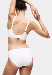 Vitt set med bh och höga trosor, med justerbara band och guldfärgade detaljer, slät textur och minimalistisk design.