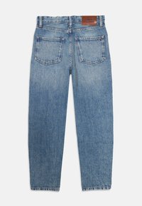 Lyseblå denimjeans med rett snitt, to baklommer og et brunt lærmerke merket "TOMMY HILFIGER" ved midjen.