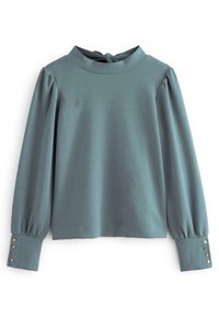 Haut à manches longues en tissu doux de couleur bleu sarcelle atténué. Caractéristiques : col montant, manches bouffantes et détails à boutons aux poignets. Texture lisse.