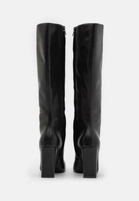 Bottes noires montant jusqu'aux genoux en cuir lisse avec une coupe ajustée, des fermetures éclair latérales et des talons carrés épais.