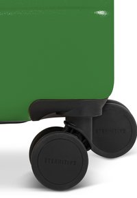 Groene harde koffer met zwarte rubberen wielen. Heeft een zachte textuur en een stevige, ronde vorm. Het wiel heeft een ETERNITIVE-merkimprint.