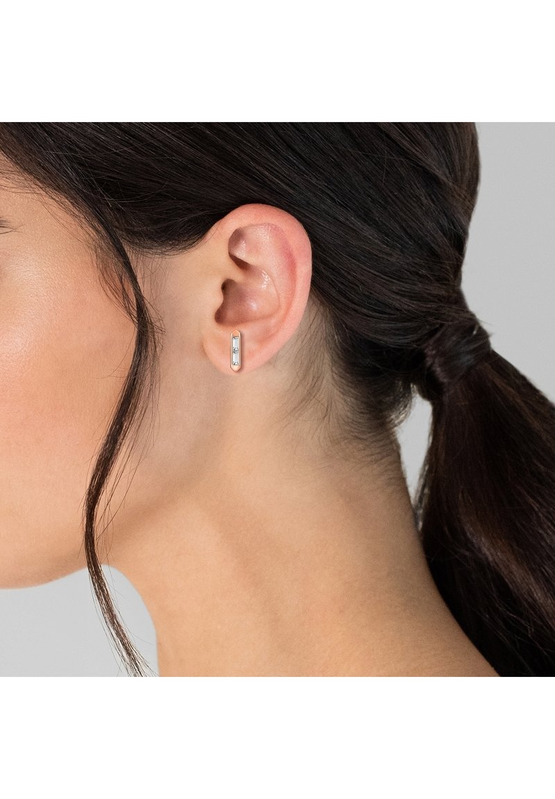 Sølv rektangulær stud ørering med en klar ædelsten, sat i et strømlinet bezel-design. Minimalistisk, poleret metalfinish, glat tekstur.