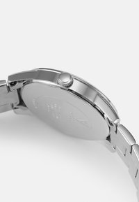 Edelstahl-Armbanduhr mit polierter Oberfläche, runder Gehäuseform und strukturiertem Krone. Verfügt über ein Metallgliederarmband und eine gravierte Rückseite.
