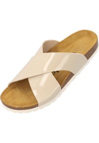 Sandalia de tiras cruzadas de charol beige con plantilla de corcho y suela de ante texturizada. Cuenta con una suela exterior de goma blanca para mayor adherencia.