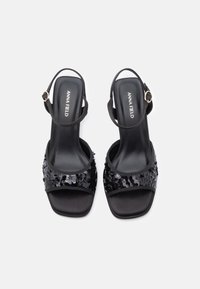 Black high-heeled sandals with a satin finish, featuring a sequin-embellished strap and adjustable ankle buckle. Open-toe design.