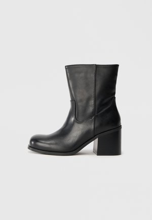 Zwarte leren enkellaars met een ronde neus, zijnaad en een blokhak. Glad textuur, eenvoudig design en een klassieke silhouette.