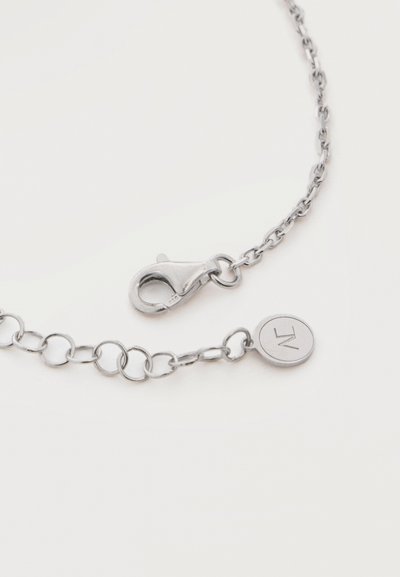 Collana a catena d'argento con chiusura a moschettone e piccolo ciondolo rotondo inciso con la lettera M, mostrata su sfondo bianco.