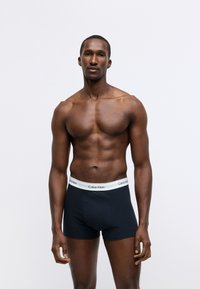 Calvin Klein men's boxer briefs in dark navy with a white logo waistband. Smooth texture and fitted design, suitable for everyday wear.