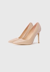 Nude patent leather high heels with pointed toes, slim stiletto heels, and a smooth, glossy finish. Interior lined in soft beige.