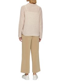 Helles rosa Strickpullover mit hohem Kragen, lockerer Passform und geripptem Muster, kombiniert mit beigen weiten Hosen und weißen Sneakers.