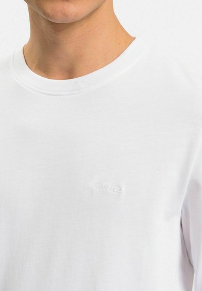 Hvid bomulds t-shirt med rund halsudskæring og et diskret, broderet "WHYRED" logo på venstre bryst. Blød tekstur med en afslappet pasform.