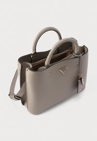 Graue Handtasche aus synthetischem Leder mit zwei Henkeln, einem abnehmbaren Riemen, goldfarbenen Beschlägen und dekorativen Nieten; verfügt über ein Reißverschlussfach.