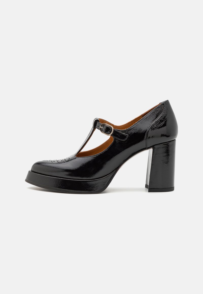 Chaussure à talon en cuir verni noir avec bride T et détail de boucle. Présente une plateforme et un bout arrondi avec des accents de design perforés.