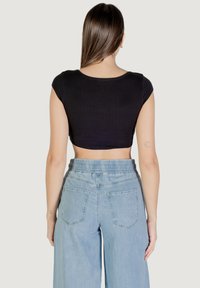 Top nero corto con maniche corte, abbinato a pantaloni di denim a gamba larga color azzurro chiaro con vita elastica e tasche posteriori.