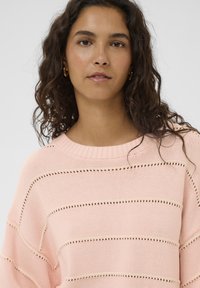 Hellrosa gestrickter Pullover mit horizontalen Streifenmustern und Lochstrick-Details, weitem Ausschnitt und lockerem Schnitt.