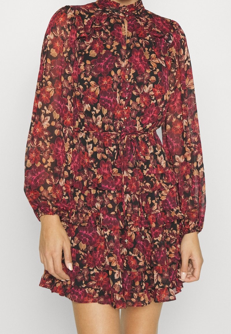 Blumenkleid mit Rüschenstufen, langen Ärmeln, hohem Kragen, dunklem Hintergrund und roten, rosa sowie cremefarbenen Blumenmustern.