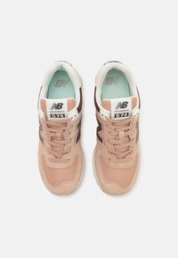 Baskets en suède et maille rose clair avec des accents brun foncé, des détails blancs et une semelle intérieure vert menthe, présentant un design à lacets et un logo.