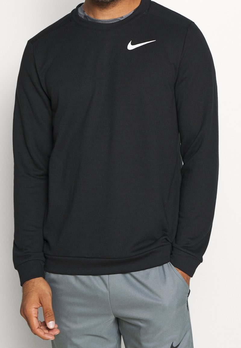 Sudadera negra de tela suave, con cuello redondo y mangas largas, presenta un logo blanco de Nike en la parte superior del pecho izquierdo.