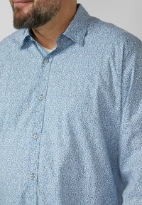 Lichtblauw overhemd met knopen en een klein bladmotief. Gemaakt van zacht stof, met een kraag en ronde knopen. Casual pasvorm.