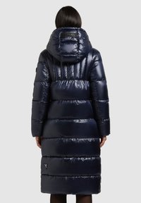 Tengerészkék pufi kabát kapucnival, steppelt mintával és sima, fényes felülettel. A hátoldalán logóval díszített.