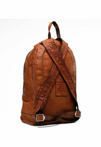 Sac à dos en cuir marron avec une finition texturée, doté de bretelles ajustables, d'un patch décoratif et d'un compartiment zippé.