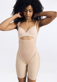 Beige body, kivágott kialakítással és állítható pántokkal. Simma textúrájú, középhosszú, minimális varrási részletekkel.