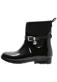 Botte de pluie noire brillante à hauteur de cheville avec une partie supérieure mate, une sangle décorative à boucle, et un petit charme logo rond sur le côté.