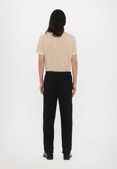 Beige short-sleeve shirt with textured stripes and white trim, paired with black pants featuring a waistband and back pocket.