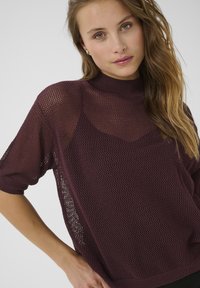 Burgundy knitted sweater with short sleeves, featuring a mesh pattern and a high neck, showcasing a loose, lightweight design.